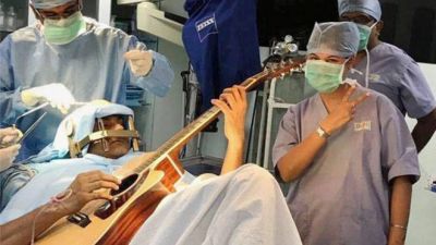 Patient plays guitar as doctors perform operation