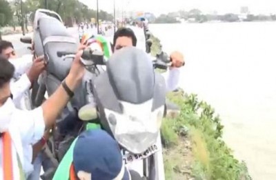 Congress workers throw own bike into the lake to protest against Modi government